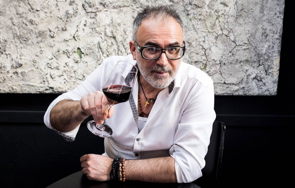 Michalis Josing im weißen Hemd mit einem Glas Rotwein