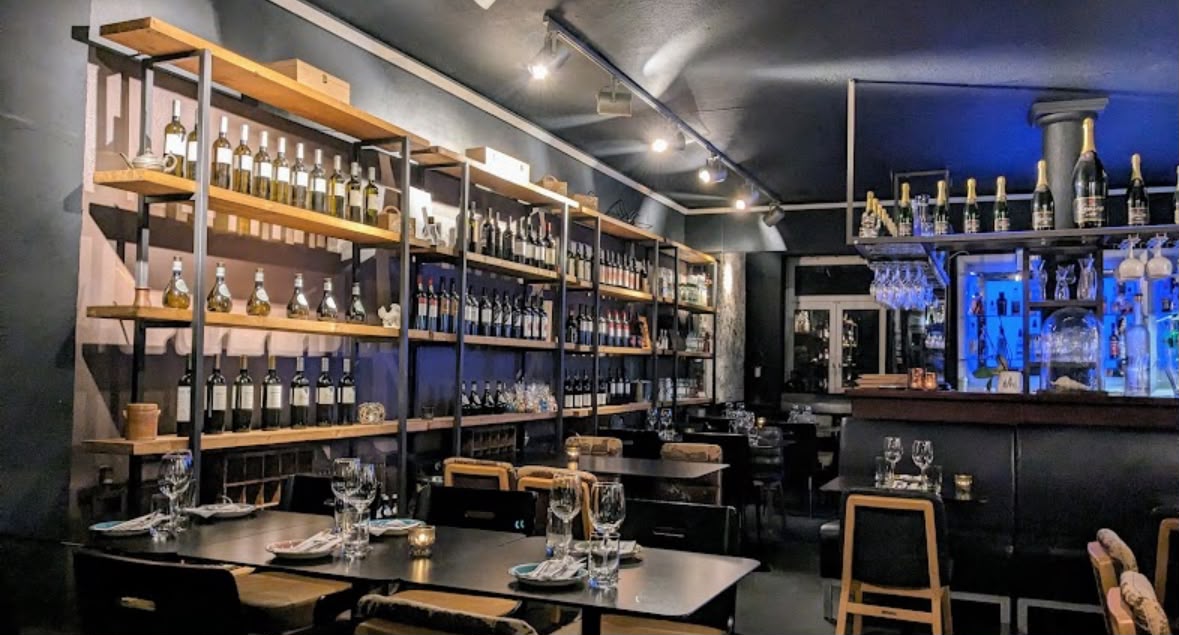 Weinregal mit zahlreichen Flaschen und Bar im Dionysos